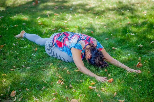 Giovane donna che pratica yoga nel parco — Foto Stock