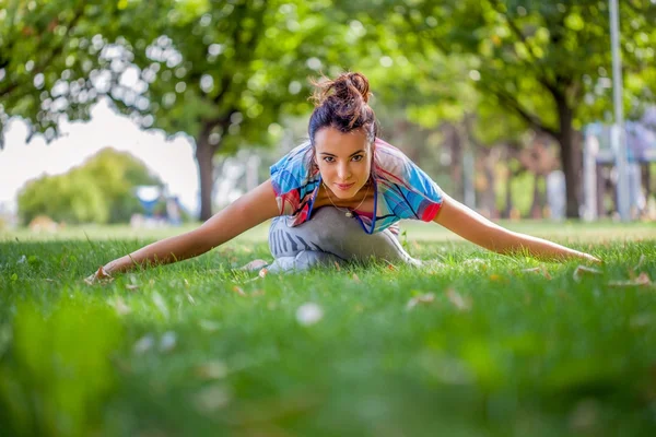 Giovane donna che pratica yoga nel parco — Foto Stock