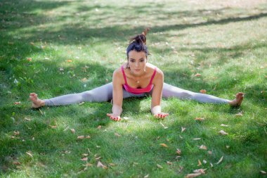 Genç kadın parkta yoga yapıyor.