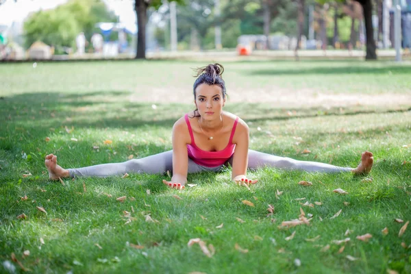 Giovane donna che pratica yoga nel parco — Foto Stock