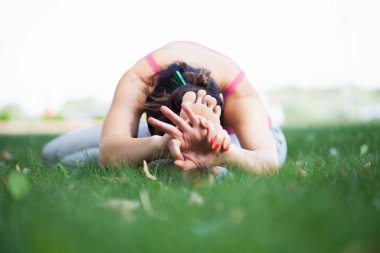 Genç kadın parkta yoga yapıyor.