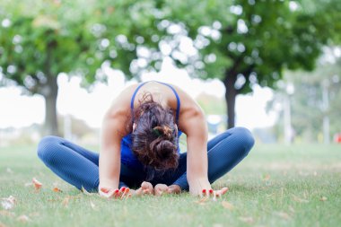 Genç kadın parkta yoga yapıyor.