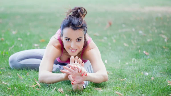 Ung kvinna utövar yoga i parken — Stockfoto