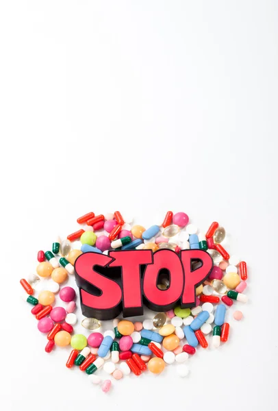 Grupo de medicamentos, pastillas y cápsulas alineados alrededor de la señal de stop en un fondo blanco. Detener el uso de drogas — Foto de Stock