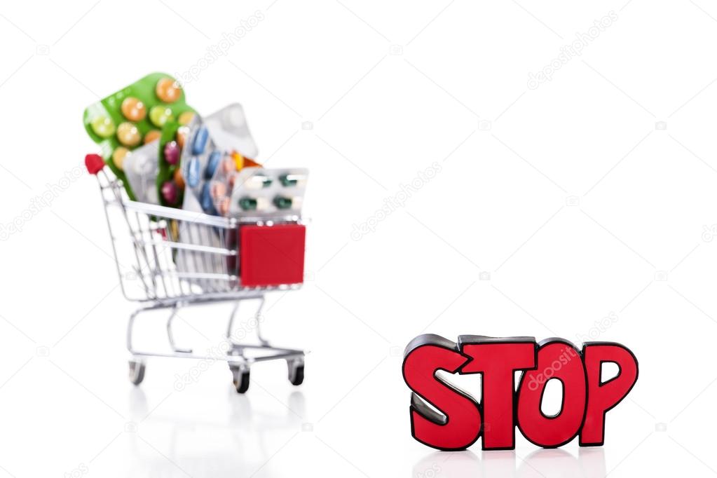 Drugs and pills in supermarket trolley with sign stop