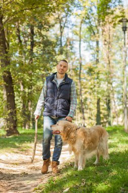 Genç adam bir köpek parkta yürüyüş 