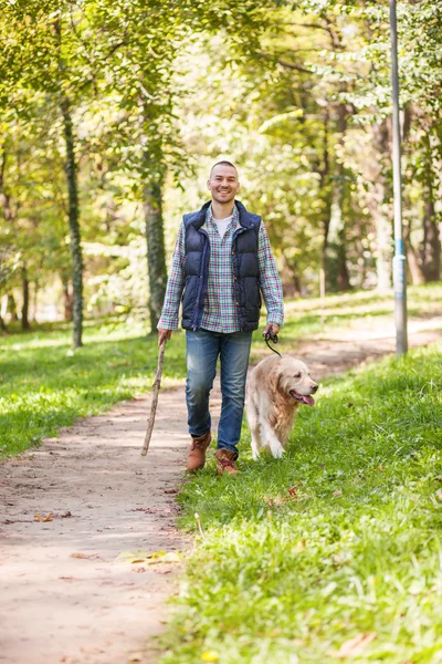 Молодий чоловік гуляє собакою в парку — стокове фото