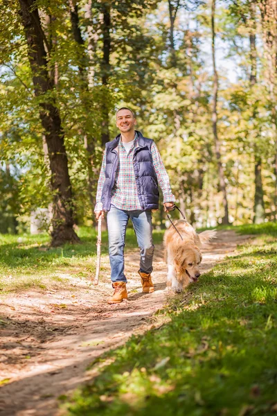 Young man walking a dog at the park — Stock Photo, Image