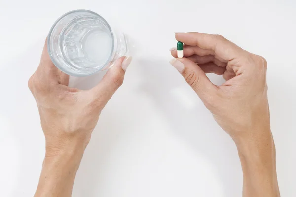 Вид зверху на жіночі руки зі склянкою води і таблеток — стокове фото