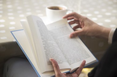 eller kadın bir kitap okuma ve bir kahve içer