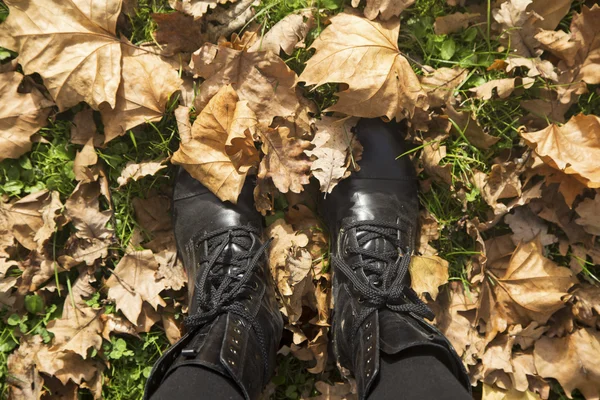 秋の葉の上のブーツで女性の足 — ストック写真