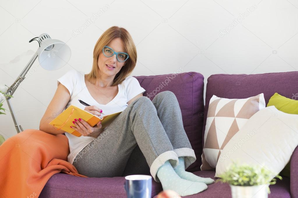 woman on the couch writing a notes