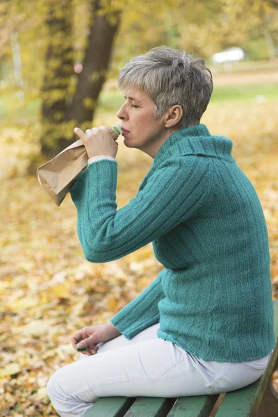 Несчастная женщина в парке пьет алкоголь — стоковое фото