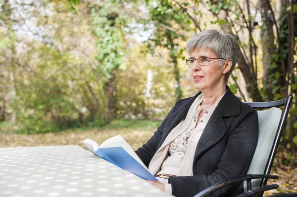 Femme plus âgée dans le parc lire un livre — Photo