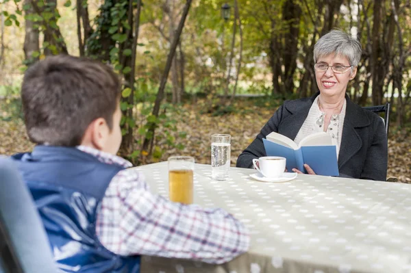 Starsza kobieta z wnukiem w parku z książką — Zdjęcie stockowe