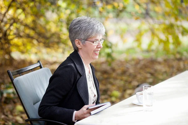 Femme plus âgée dans le parc lire un livre — Photo