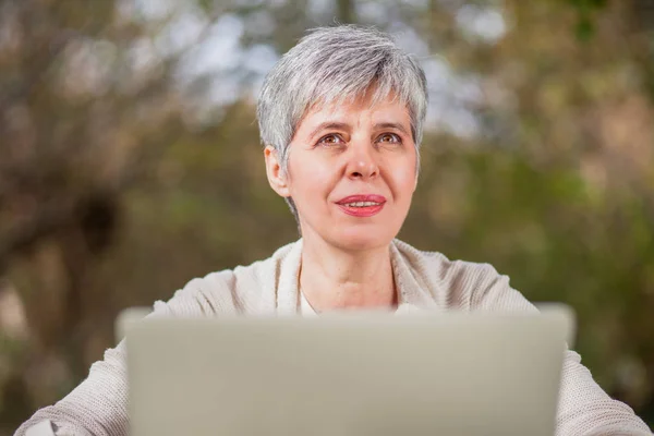 Idősebb nő, egy parkban, laptop számítógép segítségével — Stock Fotó