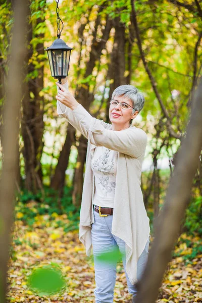 Oudere vrouw lichten lamp in de tuin — Stockfoto