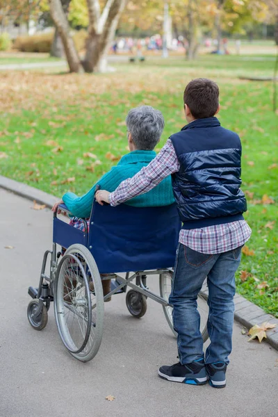 Sonson med mormor i rullstol på park — Stockfoto