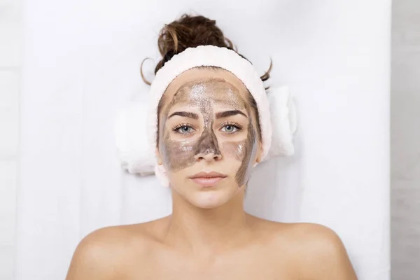 Junge Frau im Wellnessbereich mit Gesichtsmaske — Stockfoto
