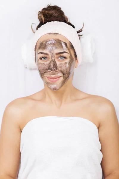 Женщина в спа-салоне с черной маской для лица — стоковое фото