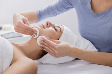woman enjoying facial massage at spa salon clipart