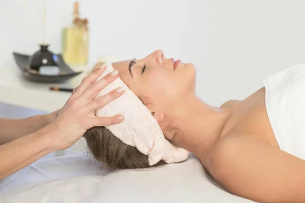 woman enjoying facial massage at spa salon