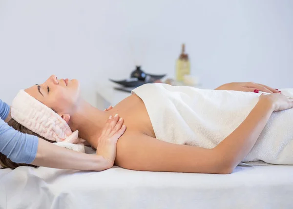 woman enjoying facial massage at spa salon