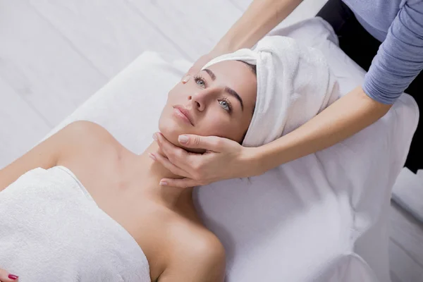 Жінка насолоджується масажем обличчя в спа-салоні — стокове фото