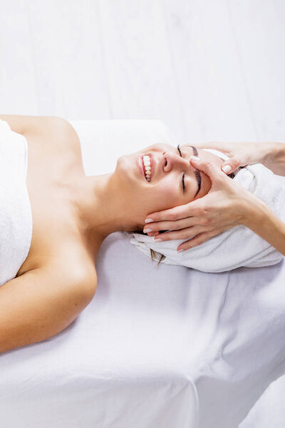 woman enjoying facial massage at spa salon