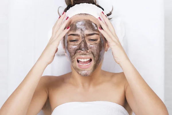 Mujer infeliz en un spa con máscara facial negra — Foto de Stock