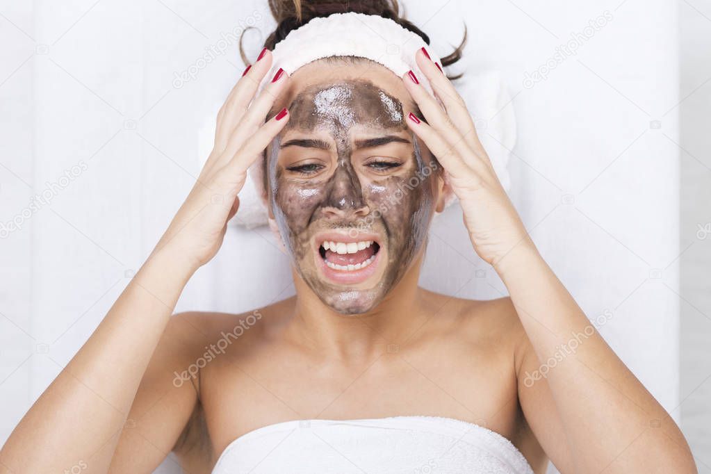 Unhappy woman in a spa with black facial mask