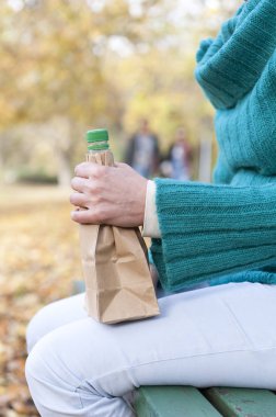 Alışveriş çantası ile alkol içki şişe tutan eller 