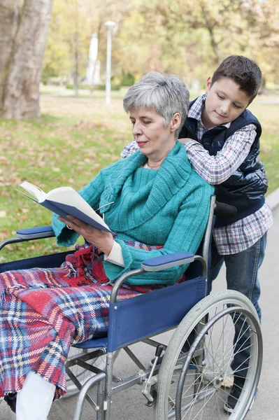 Внук с бабушкой в инвалидной коляске в парке — стоковое фото
