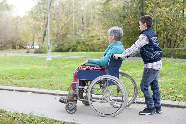 Онук штовхає його бабуся в інвалідному візку — стокове фото