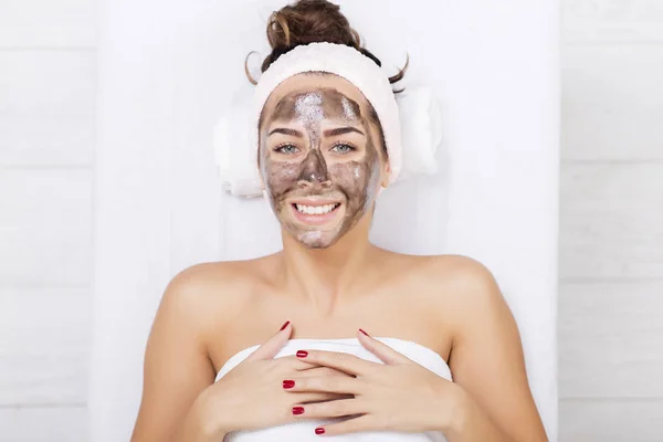 Mujer tímida en un spa con máscara facial negra — Foto de Stock
