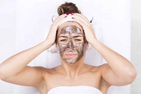 Mujer con dolor con mascarilla facial negra en spa — Foto de Stock