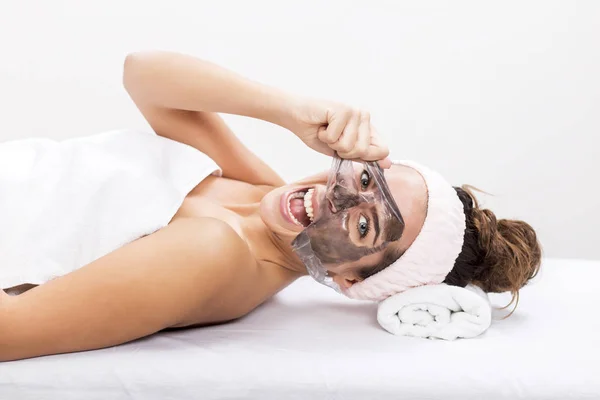 Frau im Wellnessbereich entfernt die Maske aus dem Gesicht — Stockfoto