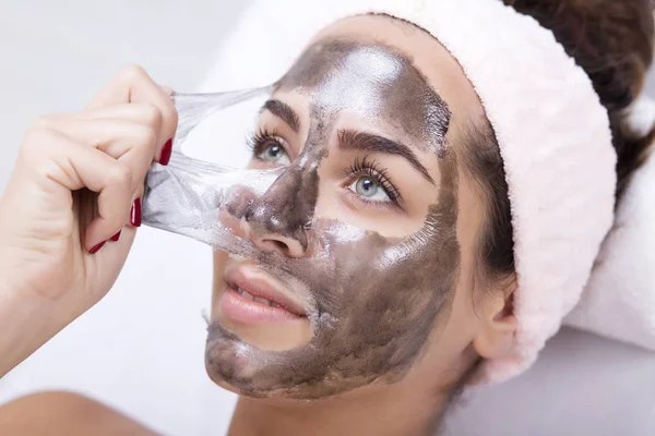 Woman in a spa salon takes off the mask from the face — Stock Photo, Image