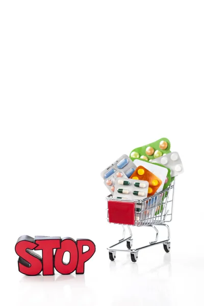 Drogas e pílulas no carrinho de supermercado com parada de sinal — Fotografia de Stock