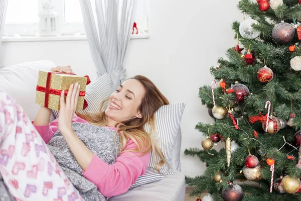 Nő feküdt a díványon, és a gazdaság egy karácsonyi ajándék — Stock Fotó