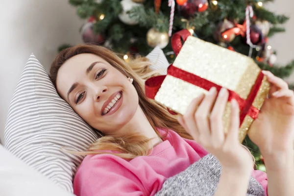 Femme couchée sur le canapé et tenant un cadeau de Noël — Photo