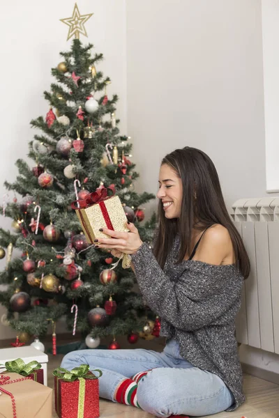 Gyönyörű nő ül karácsonyfa megnyitása bemutatja — Stock Fotó