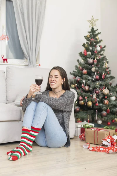 Gyönyörű nő ül a karácsonyfa élvező pohár — Stock Fotó