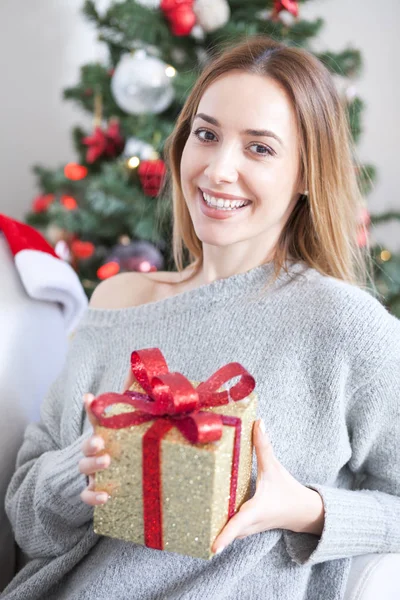 Mujer en el sofá sosteniendo un regalo de Navidad —  Fotos de Stock