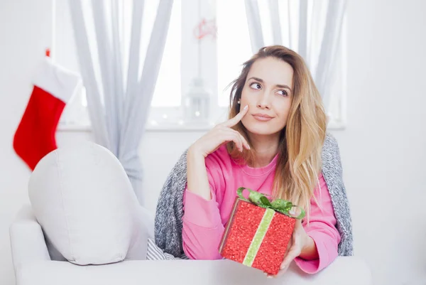 Kvinna i soffan håller en julklapp — Stockfoto