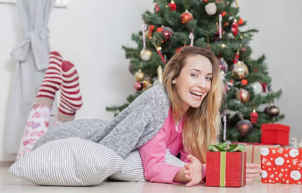 Mulher no chão segurando um presente de Natal — Fotografia de Stock