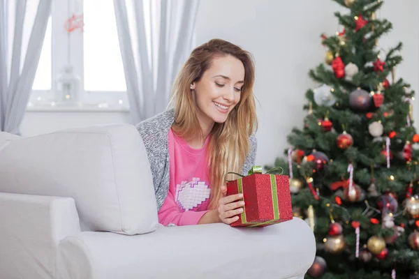 Femme sur le canapé tenant un cadeau de Noël — Photo