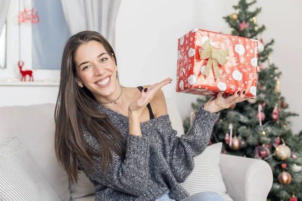 Mujer al lado del árbol de Navidad con un regalo —  Fotos de Stock