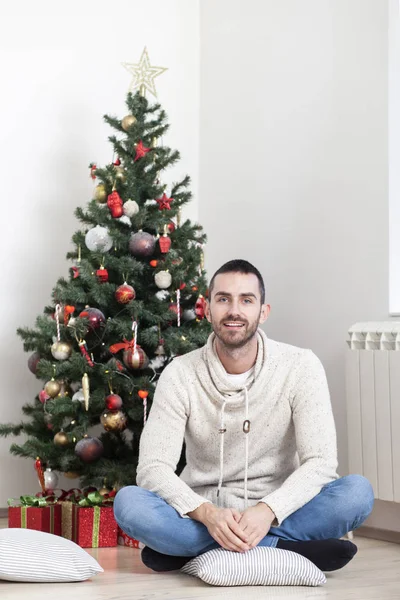 Homme assis à côté de l'arbre de Noël — Photo